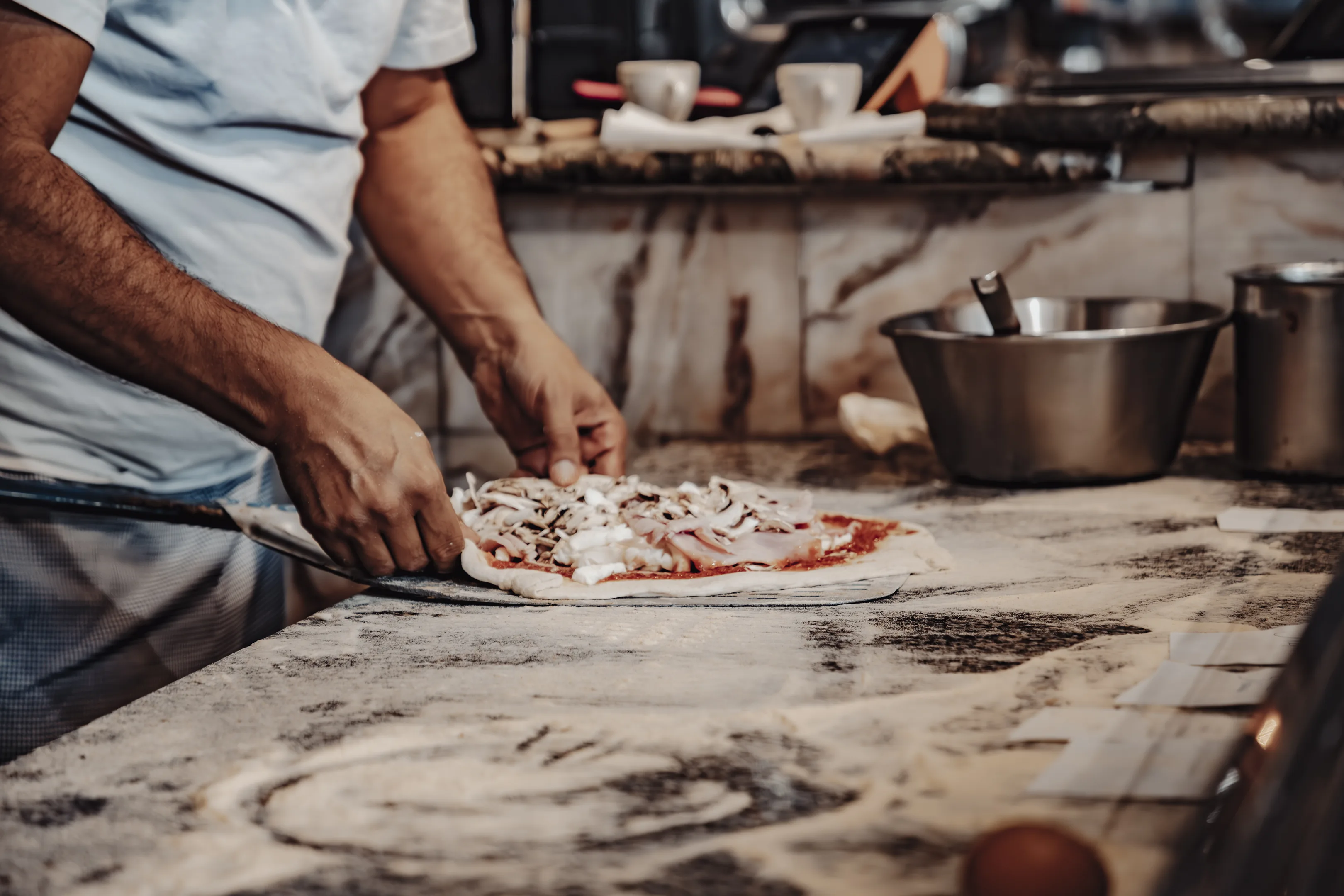 Pizzaiolo garnissant une pizza aux champignons