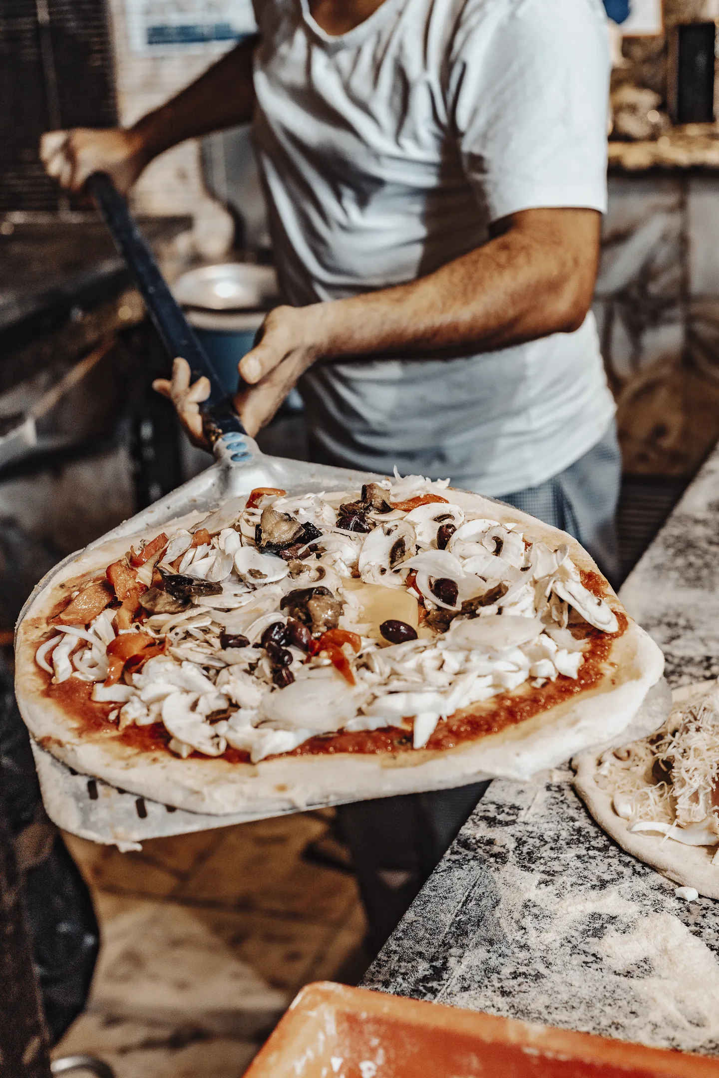 Pizzaiolo de La Dolce Vita préparant une pizza au four à bois